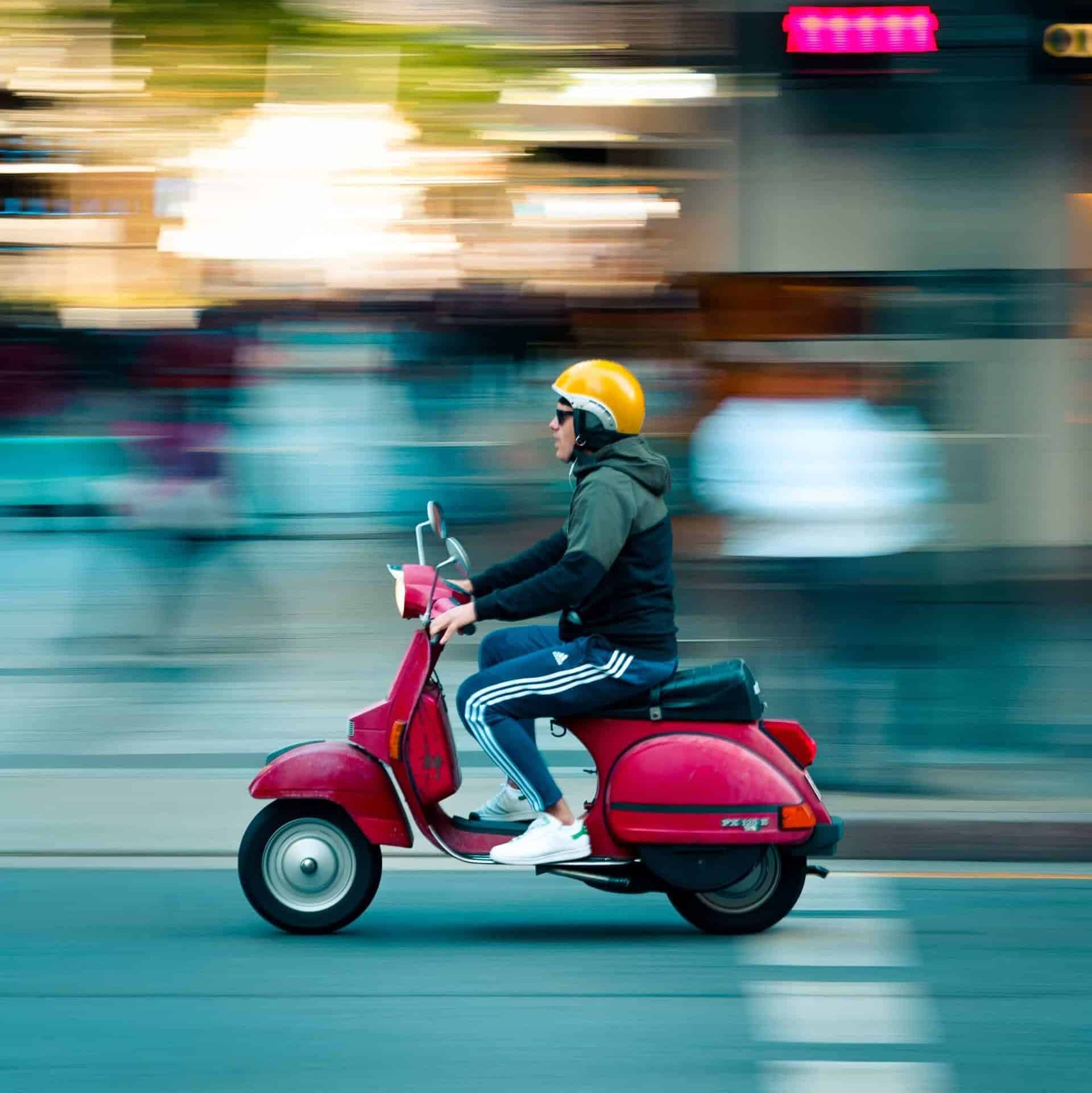 Man riding red motor scooter